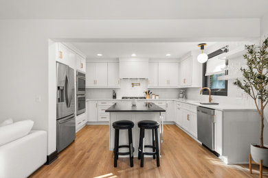Eat-in kitchen - 1950s u-shaped light wood floor eat-in kitchen idea in Nashville with a drop-in sink, beaded inset cabinets, white cabinets, white backsplash, subway tile backsplash, stainless steel appliances, an island and white countertops