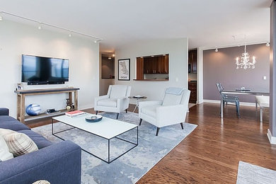 Mittelgroßes Stilmix Wohnzimmer mit grauer Wandfarbe, braunem Holzboden und TV-Wand in Chicago
