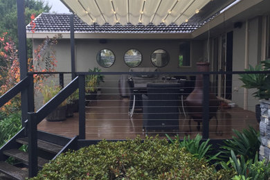 This is an example of a large country courtyard deck in Melbourne with a pergola.