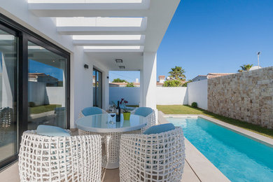 Ejemplo de terraza minimalista de tamaño medio en patio trasero con suelo de baldosas y pérgola
