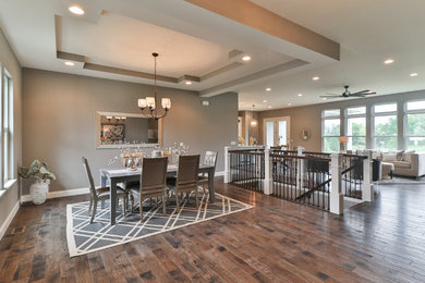 Example of a mid-sized transitional dark wood floor and brown floor great room design in St Louis with gray walls and no fireplace