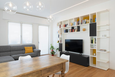Esempio di un soggiorno minimalista di medie dimensioni e aperto con libreria, pareti bianche, pavimento in legno verniciato e TV autoportante