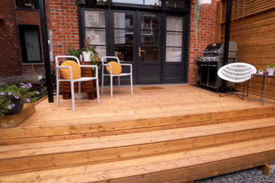 Example of a small arts and crafts backyard ground level privacy deck design in Montreal