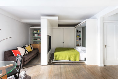 Small contemporary bedroom in New York with white walls and medium hardwood floors.