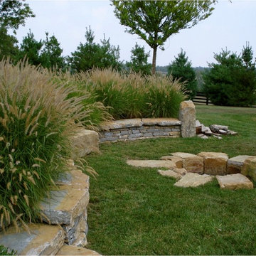 Sandstone boulder fire pit floating in turf with limestone sit wall wrapping aro