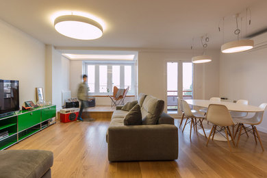 Foto de salón para visitas abierto contemporáneo grande sin chimenea con paredes blancas, suelo de madera en tonos medios y pared multimedia