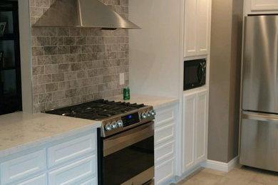 Inspiration for a contemporary ceramic tile eat-in kitchen remodel in San Diego with raised-panel cabinets, white cabinets, marble countertops, beige backsplash, brick backsplash and stainless steel appliances