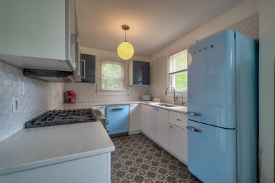 Photo of a small contemporary u-shaped eat-in kitchen in Wilmington with a single-bowl sink, flat-panel cabinets, blue cabinets, quartz benchtops, white splashback, mosaic tile splashback, coloured appliances, ceramic floors, no island, grey floor and white benchtop.
