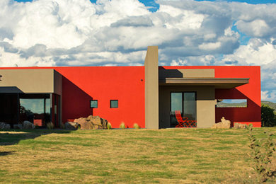 This is an example of a large contemporary one-storey stucco red exterior in Albuquerque with a flat roof.