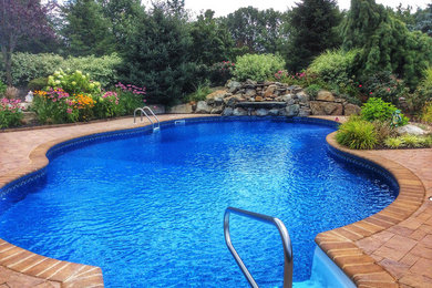 Design ideas for a large traditional backyard custom-shaped natural pool in New York with a water feature and natural stone pavers.