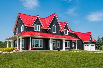 Example of a country black two-story vinyl and board and batten house exterior design in Toronto with a red roof
