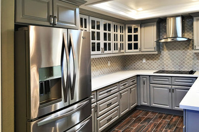 Example of a mid-sized transitional u-shaped medium tone wood floor eat-in kitchen design in Orange County with raised-panel cabinets, gray cabinets, quartz countertops, a peninsula, a double-bowl sink, brown backsplash, mosaic tile backsplash and stainless steel appliances