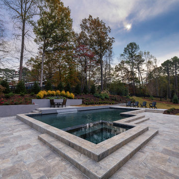 Contemporary style pool with silver travertine deck and custom water feature