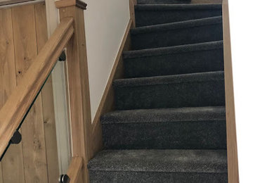 Small rustic carpeted l-shaped glass railing staircase in Other with carpeted risers.