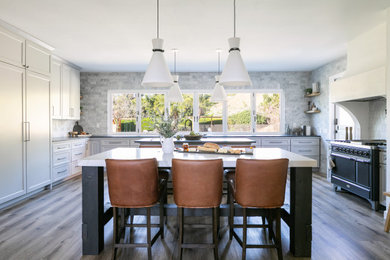 Transitional medium tone wood floor and brown floor kitchen photo in Orange County with shaker cabinets, white cabinets, gray backsplash, black appliances, two islands and gray countertops