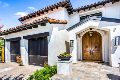 Mediterranean white two-story stucco exterior home idea in Orange County with a tile roof
