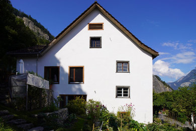 Exemple d'une façade de maison blanche en stuc à deux étages et plus avec un toit à deux pans.