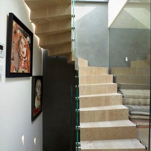 Photo of a medium sized contemporary wood spiral glass railing staircase in London with wood risers.