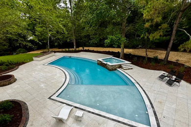 Mid-sized elegant backyard stone and custom-shaped pool landscaping photo in Other