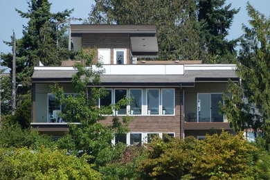 Inspiration for a large contemporary three-storey brown house exterior in Seattle with mixed siding, a flat roof and a shingle roof.