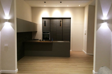 Immagine di una grande cucina design con lavello da incasso, ante lisce, ante marroni, top in quarzo composito, paraspruzzi marrone, paraspruzzi con piastrelle a listelli, elettrodomestici neri, parquet chiaro e penisola