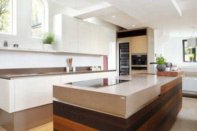 Inspiration for a mid-sized contemporary single-wall open plan kitchen in Sussex with an undermount sink, flat-panel cabinets, dark wood cabinets, solid surface benchtops, panelled appliances, concrete floors and with island.