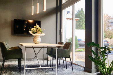 Arbeitszimmer mit grauer Wandfarbe, Teppichboden, freistehendem Schreibtisch und grauem Boden in Sonstige