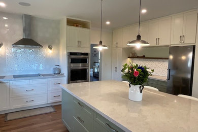 Kitchen photo in Toronto with shaker cabinets, white cabinets, stainless steel appliances, an island and beige countertops