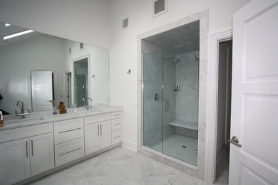 Large contemporary master bathroom in New York with shaker cabinets, white cabinets, an alcove shower, gray tile, marble, white walls, marble floors, grey floor and a hinged shower door.