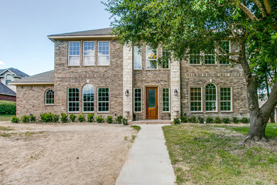 Photo of a large traditional two-storey brick beige house exterior in Dallas with a hip roof and a shingle roof.
