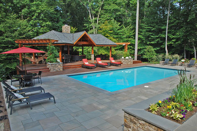 Large asian backyard rectangular natural pool in DC Metro with a pool house and natural stone pavers.