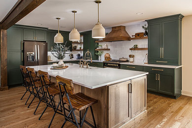 Example of a mid-sized farmhouse medium tone wood floor and exposed beam open concept kitchen design in Detroit with a farmhouse sink, shaker cabinets, green cabinets, quartz countertops, white backsplash, an island and white countertops