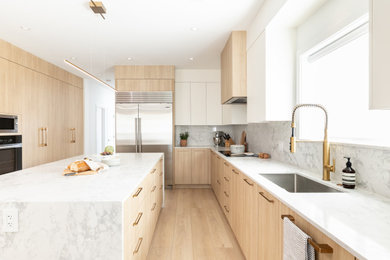 Example of a mid-sized trendy l-shaped light wood floor and beige floor eat-in kitchen design in Vancouver with flat-panel cabinets, light wood cabinets, quartz countertops, white backsplash, quartz backsplash, stainless steel appliances, an island and white countertops