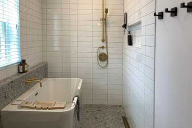 モントリオールにある中くらいなおしゃれなマスターバスルーム (ドロップイン型浴槽、シャワー付き浴槽	、壁掛け式トイレ、白いタイル、セラミックタイル、白い壁、グレーの床、オープンシャワー) の写真