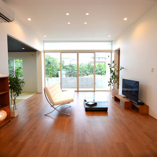 Exempel på ett modernt allrum med öppen planlösning, med vita väggar, plywoodgolv, en fristående TV och brunt golv