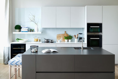 This is an example of a contemporary eat-in kitchen in Gloucestershire with flat-panel cabinets and grey cabinets.