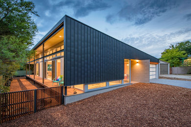 Photo of a large contemporary one-storey black exterior in Canberra - Queanbeyan with metal siding and a flat roof.
