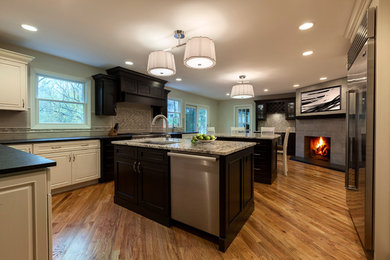 Eat-in kitchen - huge transitional l-shaped medium tone wood floor and brown floor eat-in kitchen idea in New York with an undermount sink, raised-panel cabinets, white cabinets, granite countertops, gray backsplash, ceramic backsplash, stainless steel appliances and two islands