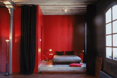 Diseño de dormitorio tipo loft actual de tamaño medio con paredes rojas y suelo de cemento