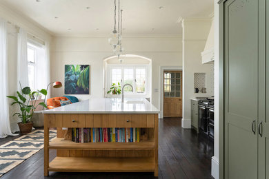 Photo of a medium sized classic kitchen in Berkshire with an integrated sink, medium wood cabinets, quartz worktops, black appliances, dark hardwood flooring, an island and white worktops.