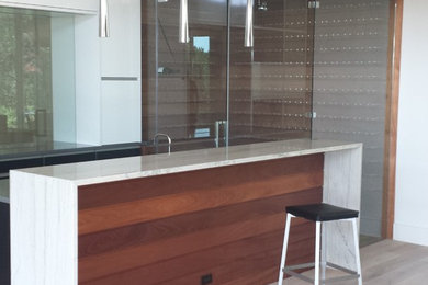 Example of a mid-sized minimalist single-wall light wood floor open concept kitchen design in Austin with an island, medium tone wood cabinets and granite countertops