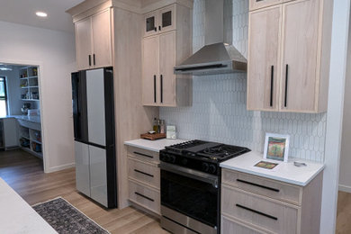 Inspiration for a large transitional l-shaped vinyl floor and brown floor eat-in kitchen remodel in Other with a double-bowl sink, shaker cabinets, light wood cabinets, quartzite countertops, white backsplash, ceramic backsplash, stainless steel appliances, an island and white countertops