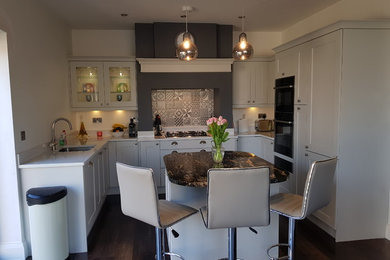 This is an example of a medium sized modern u-shaped open plan kitchen in Other with a submerged sink, shaker cabinets, grey cabinets, engineered stone countertops, grey splashback, vinyl flooring, an island and brown floors.