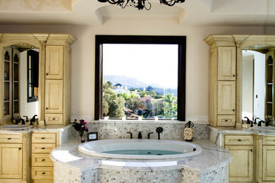 Example of a large tuscan master beige tile, gray tile, white tile and mosaic tile marble floor bathroom design in Los Angeles with raised-panel cabinets, beige cabinets, beige walls, a drop-in sink and marble countertops