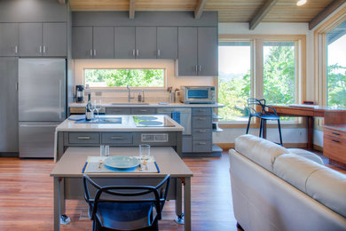 Design ideas for a mid-sized transitional galley open plan kitchen in Portland with an undermount sink, flat-panel cabinets, blue cabinets, quartz benchtops, stainless steel appliances, medium hardwood floors and with island.