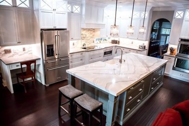 Photo of a large transitional u-shaped separate kitchen in Miami with a farmhouse sink, recessed-panel cabinets, white cabinets, quartzite benchtops, multi-coloured splashback, matchstick tile splashback, stainless steel appliances, dark hardwood floors, with island, brown floor and white benchtop.