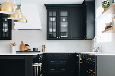 Example of a large transitional u-shaped light wood floor and brown floor eat-in kitchen design in Chicago with an undermount sink, shaker cabinets, black cabinets, quartz countertops, white backsplash, subway tile backsplash, stainless steel appliances, an island and white countertops