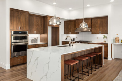 Example of a large trendy medium tone wood floor and beige floor kitchen design in Dallas with an undermount sink, shaker cabinets, dark wood cabinets, quartz countertops, stainless steel appliances, an island, white backsplash, glass tile backsplash and multicolored countertops