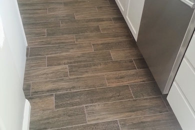 Mid-sized trendy porcelain tile and brown floor kitchen photo in San Diego with a farmhouse sink, shaker cabinets, white cabinets, stainless steel appliances and no island