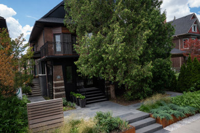 Immagine di un giardino formale minimalista esposto in pieno sole di medie dimensioni e davanti casa in estate con un muro di contenimento, pavimentazioni in pietra naturale e recinzione in legno